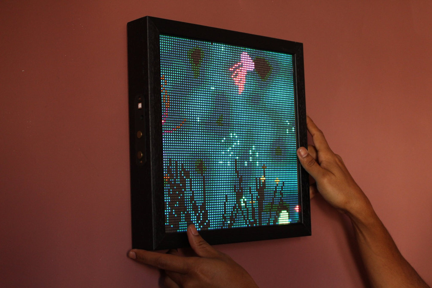 Livegrid - Digital art piece on a LED display frame held by a person against a pink wall.